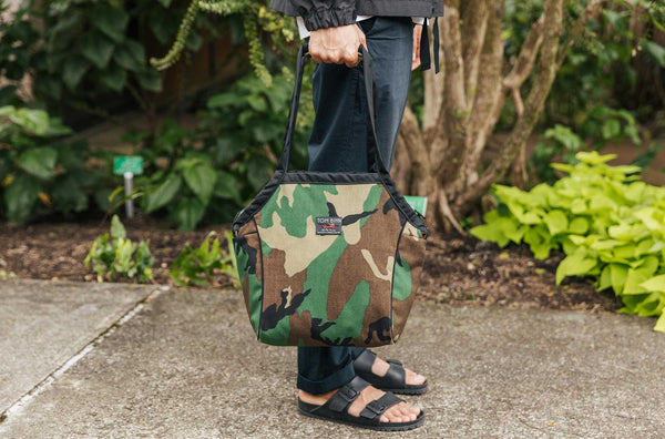 Person standing and carrying the Zip-Top Shop Bag, Size Small, in Beaver Camo.